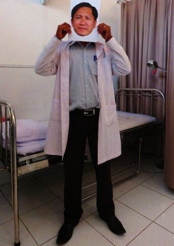 A doctor holding a photo of Ny Sokha in his clinic