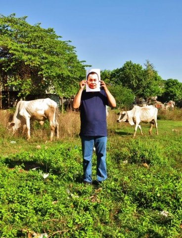 A man holding a photo of Yi Soksan in a farm on the surroundings